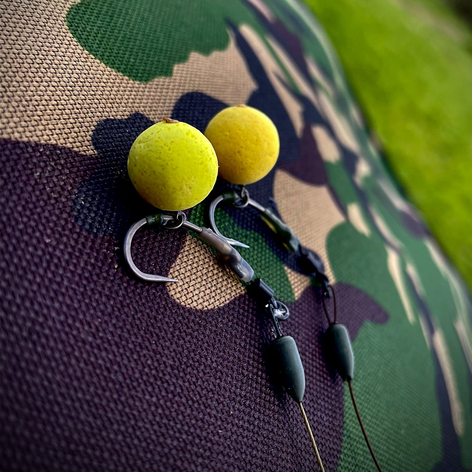 two carp rigs with hooks and a yellow max attract baits popup attached to each hook, layed on top of a bivvy