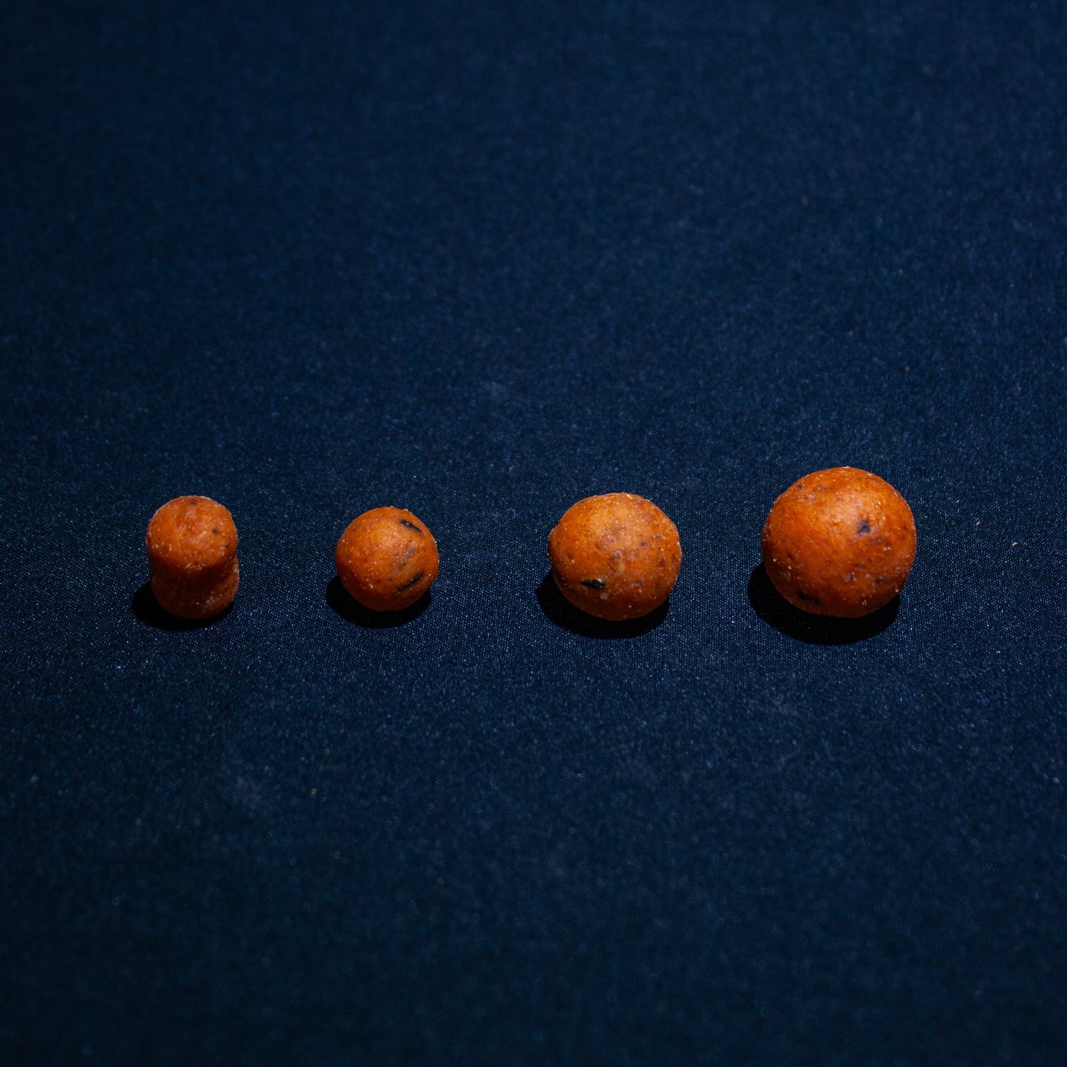 four max attract baits fruit salad boilies in line on a black back ground showcasing the different sizes of boilies