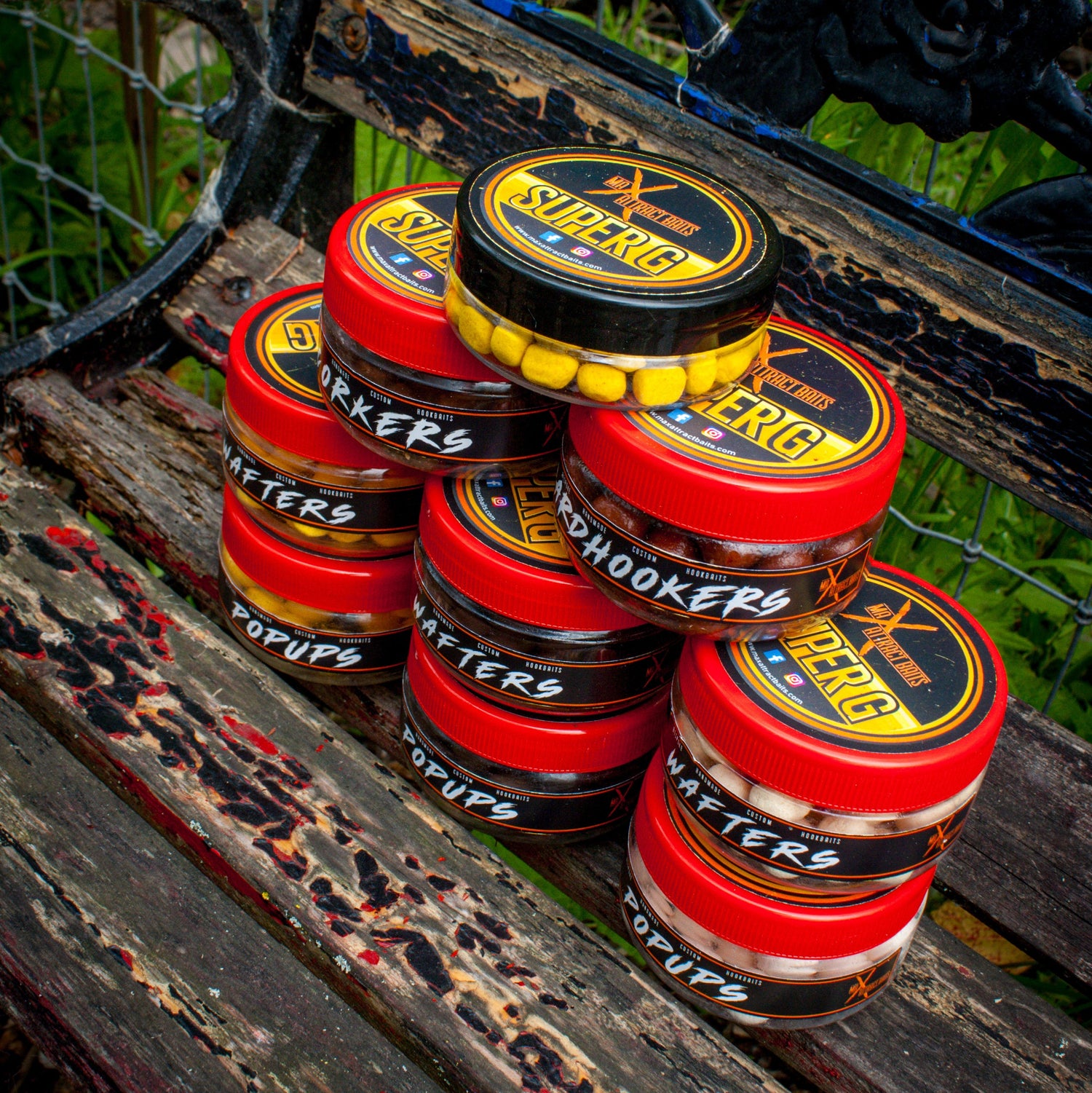 pots of max attract baits super g hook baits stacked on top of each other on an old bench