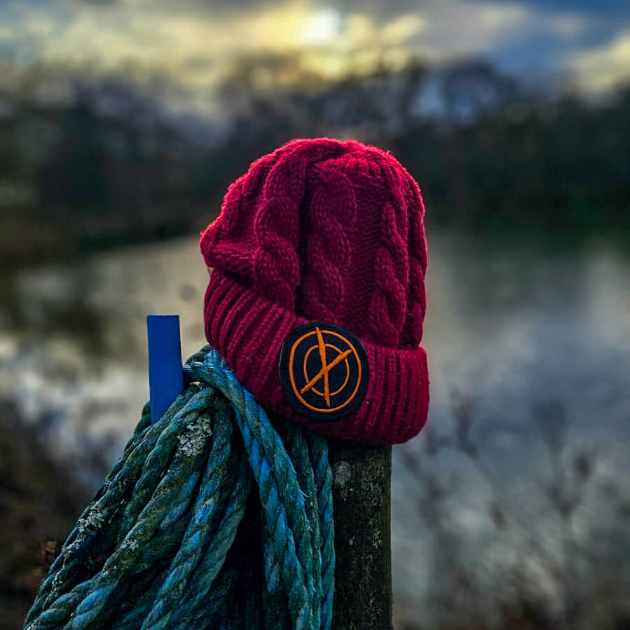 red max attract baits bobble hat on a fence post which has blue rope wrapped around it, over looking carp lake