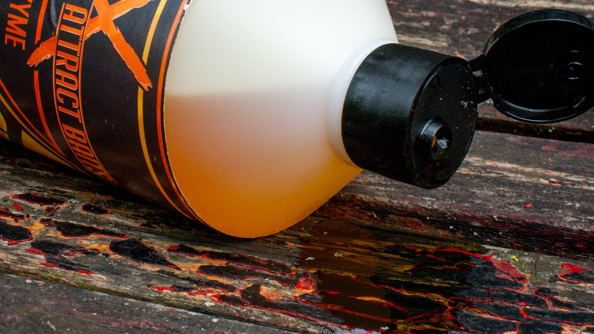 max attract baits carp oil bottle layed side ways with oil dripping from the lid onto a wooden surface